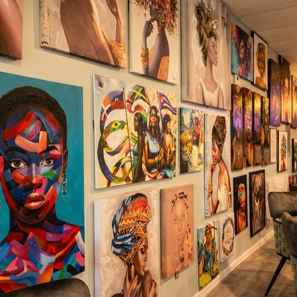 A restaurant interior with vibrant, colorful paintings of women on the walls and modern seating.