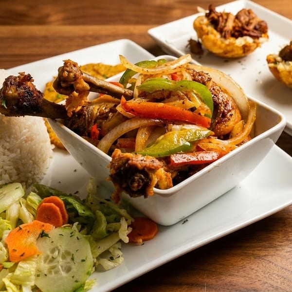 Chicken and vegetable stir-fry with white rice, salad, and plantain cups filled with meat.