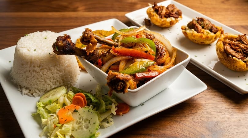 Chicken and vegetable stir-fry with white rice, salad, and plantain cups filled with meat.